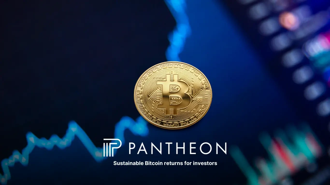 Gold Bitcoin coin positioned in the foreground against a blurred trading screen displaying blue and red market charts.